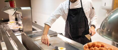 Un chef preparando comida en una cocina con una plancha, un bol de huevos y un dispensador de agua.