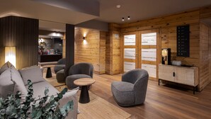 A modern interior with a sofa, armchairs, a small table, and a cabinet.