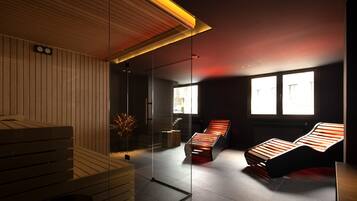 A modern spa room with wooden benches, a glass partition, and a ceiling light.
