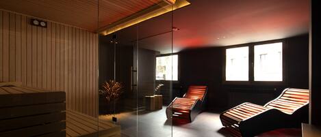 Un spa moderno con bancos de madera, un separador de vidrio y una lámpara en el techo.