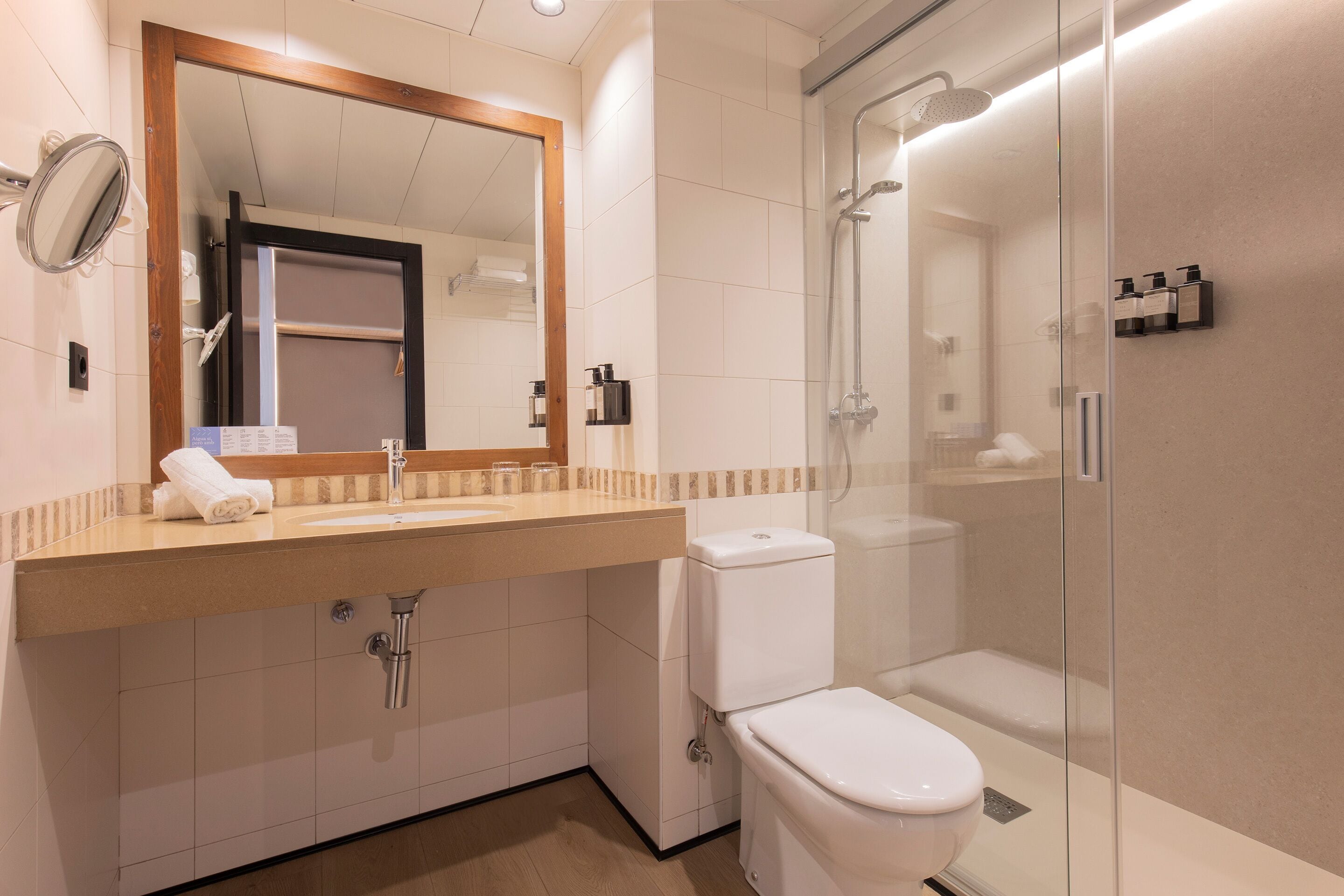 Un bagno moderno con lavandino, specchio, WC e cabina doccia in vetro.
