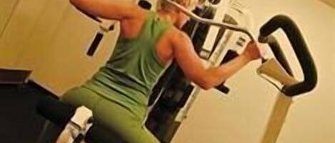 A person using a leg press machine in a gym with a simple layout and basic equipment.