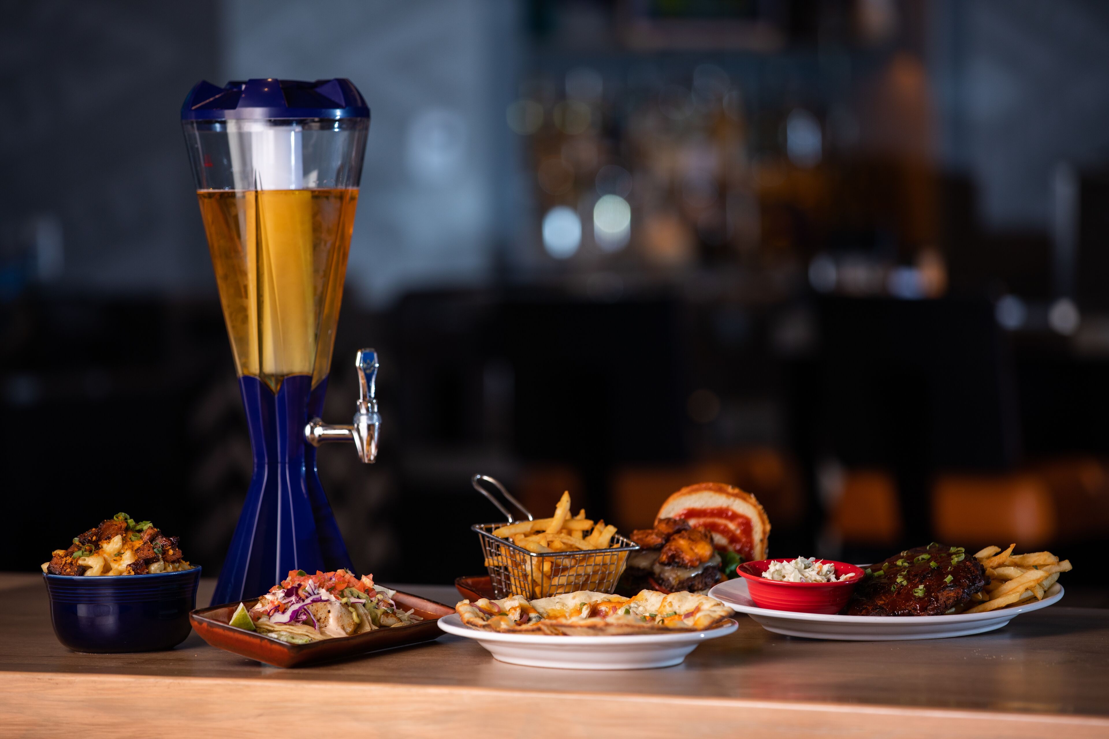 A bar setting with a beer tap, various dishes including a burger, fries, and a salad.