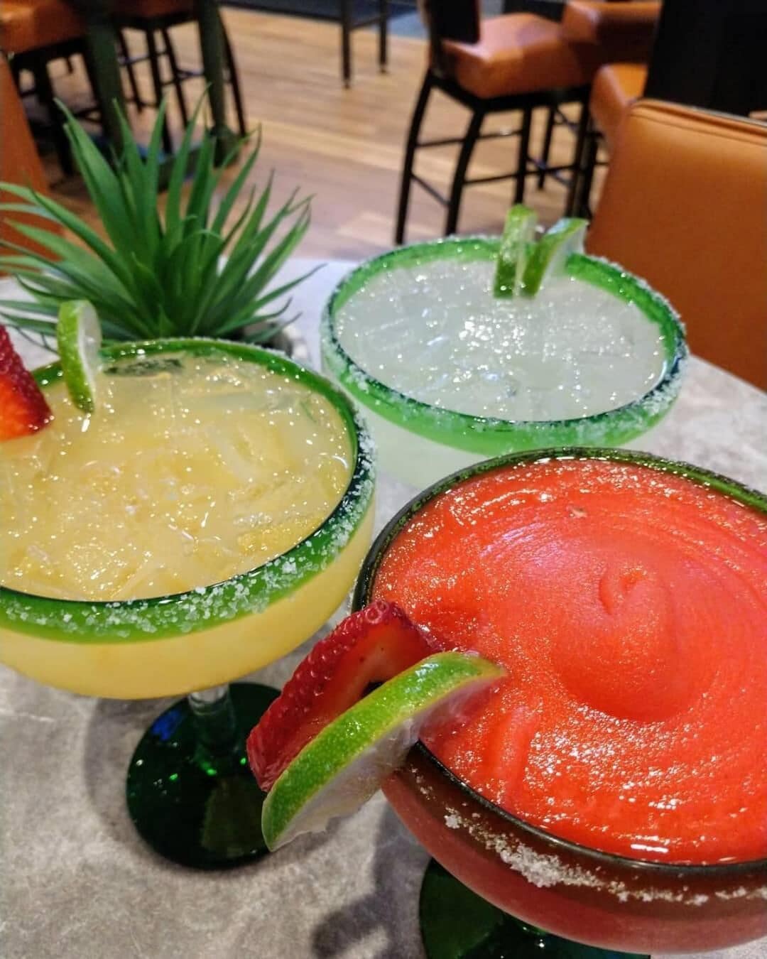 Drei Cocktails mit Limettenscheiben auf einem Tisch.