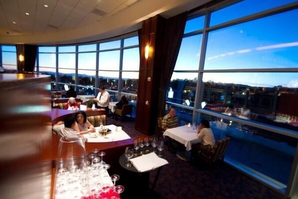 A restaurant with tables set for dining, large windows offering a view, and a bar area. - Gold Country Casino Resort (Oroville)