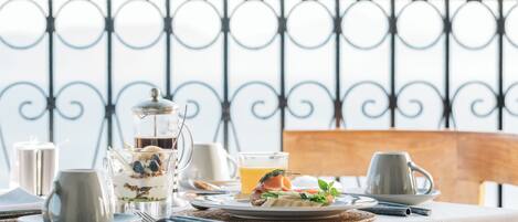 A breakfast table set with a glass of orange juice, a plate with eggs, toast, and a pastry, and a pitcher of milk.
