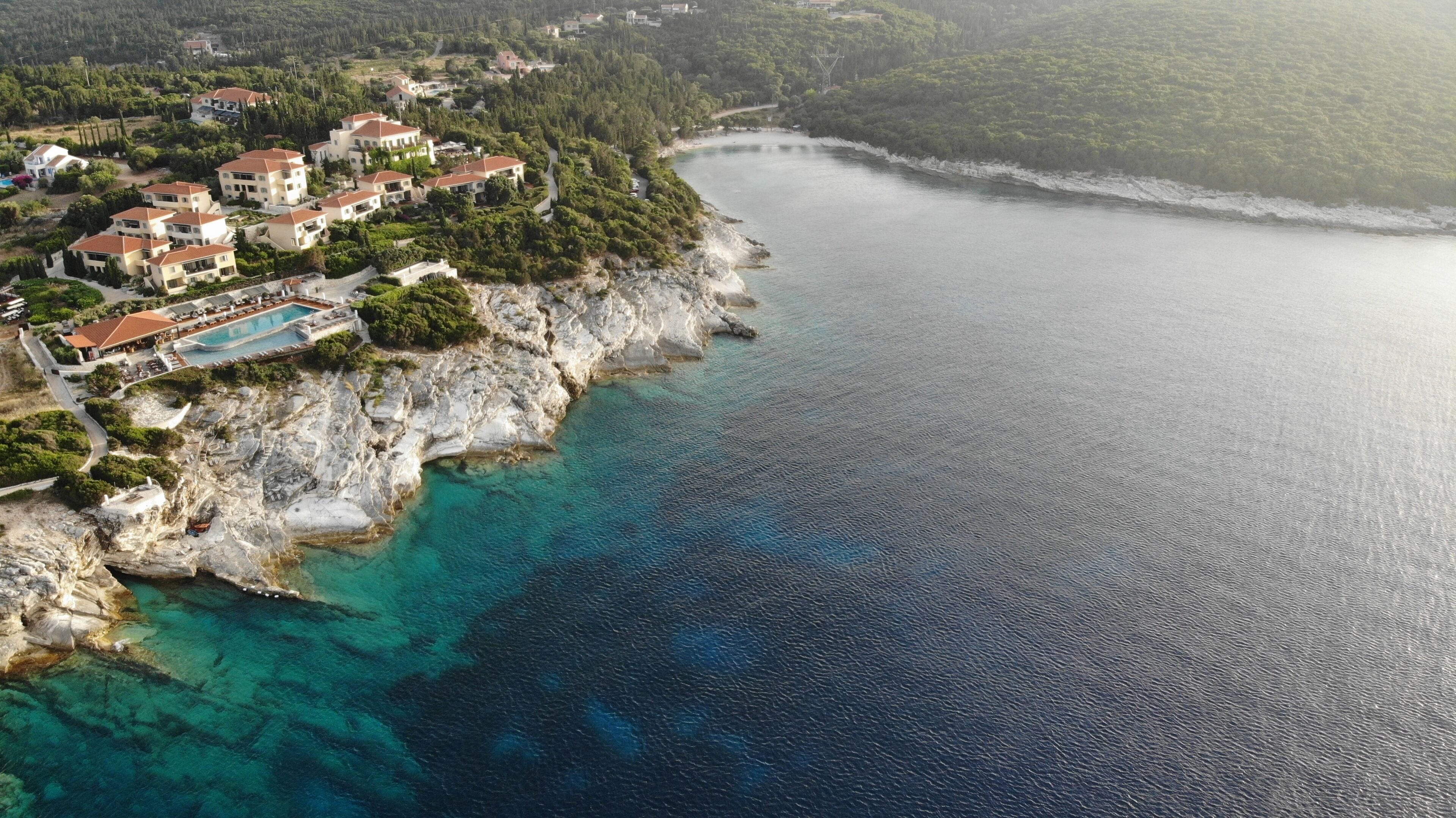 Vista aérea de una zona costera con un conjunto de casas y una piscina.