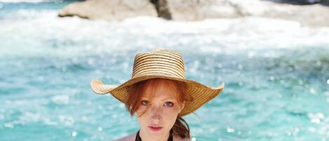 A person standing by a rocky shoreline with clear blue water.