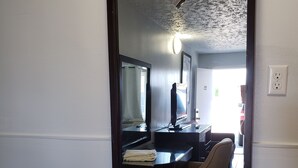 A hotel room with a large mirror, a desk, a chair, and a bed. - Niagara Falls Courtside Inn (Niagara Falls)