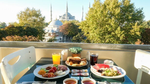 A table with breakfast items and a view of a mosque with domes and minarets.