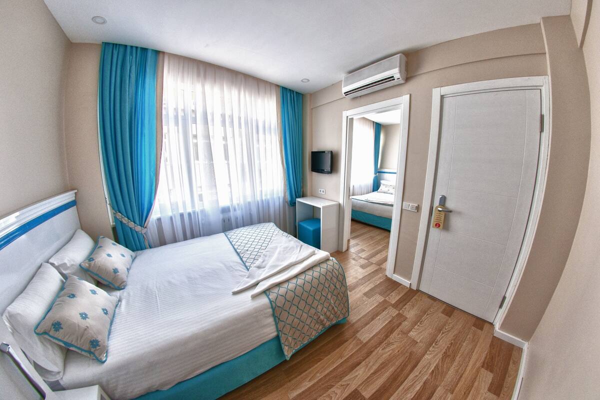 Une chambre d’hôtel avec un lit, un bureau, une télévision et une porte.