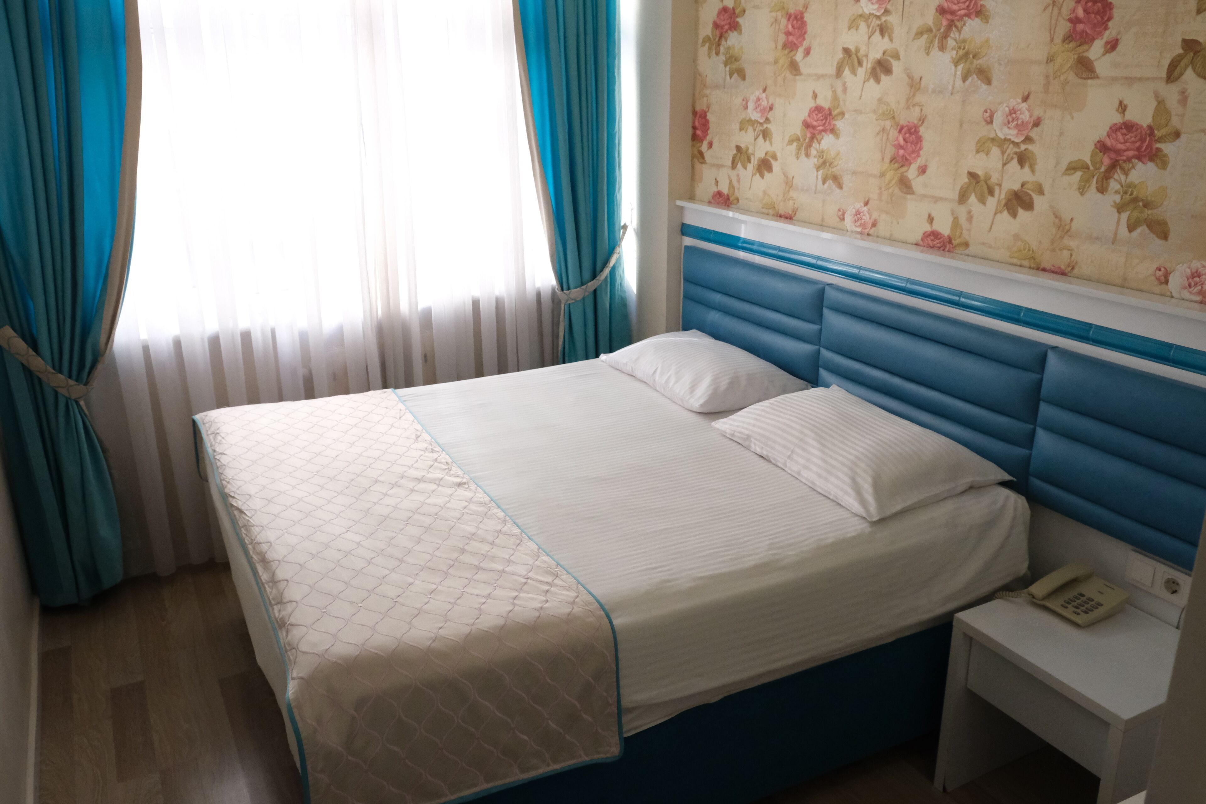 Una cama bien hecha con un cubrecolchón acolchado, un teléfono en la mesita de noche y una mesita de noche.