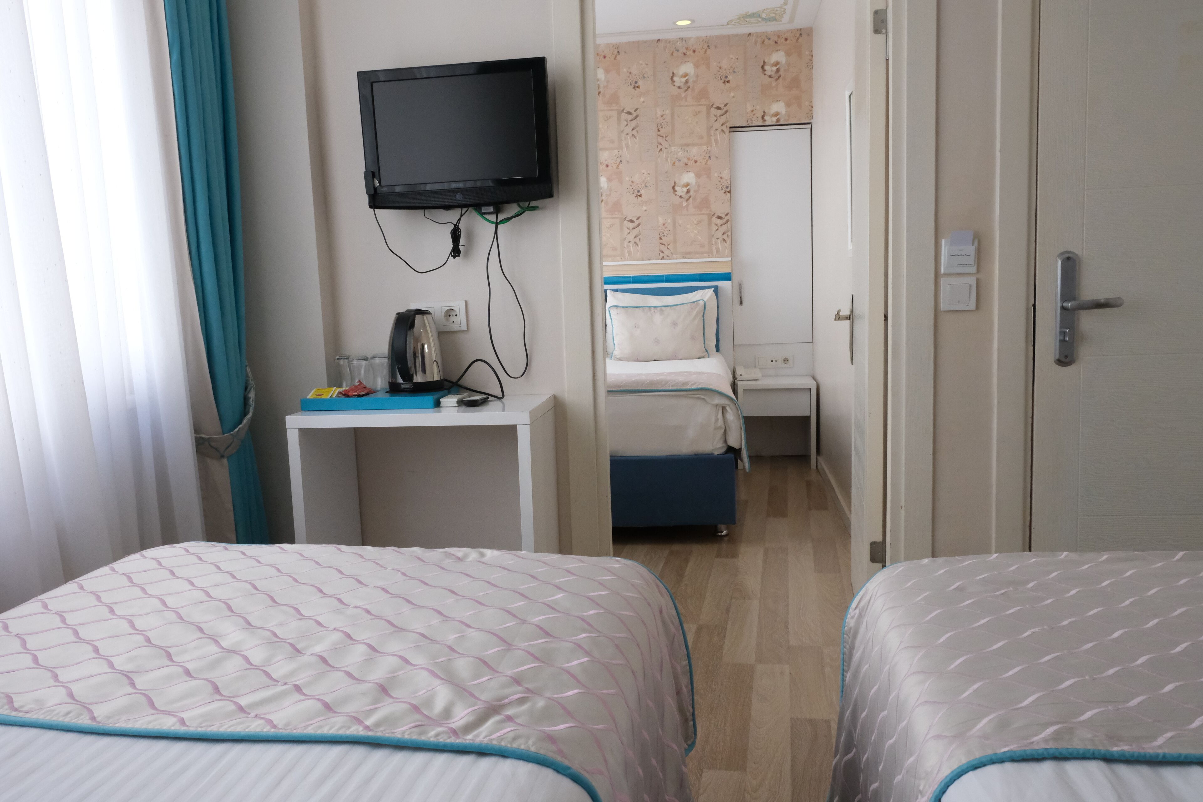 Une chambre d’hôtel avec deux lits, un bureau, une télévision et une salle de bain visible à travers une porte ouverte.