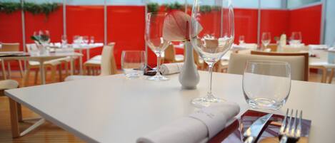 A restaurant with white tables, red walls, and hanging lights.