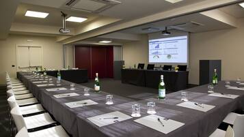A conference room with a long table, chairs, a projector screen, and a presentation on the wall.