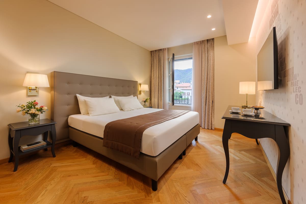 Une chambre d’hôtel avec un grand lit, deux tables de chevet, un téléviseur à écran plat et une vue sur la ville.