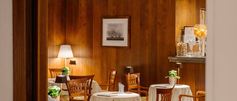 A dining area with wooden panel walls, white tablecloths, and wooden chairs.