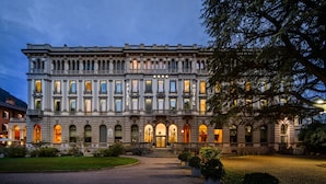 A historic hotel with a grand facade, multiple balconies, and a well-lit entrance. - Palace Hotel (Como)