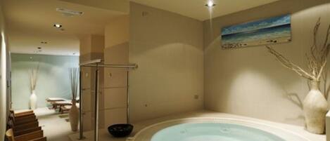 A spa room with a hot tub, a wooden bench, a towel rack, and a painting of a beach scene.