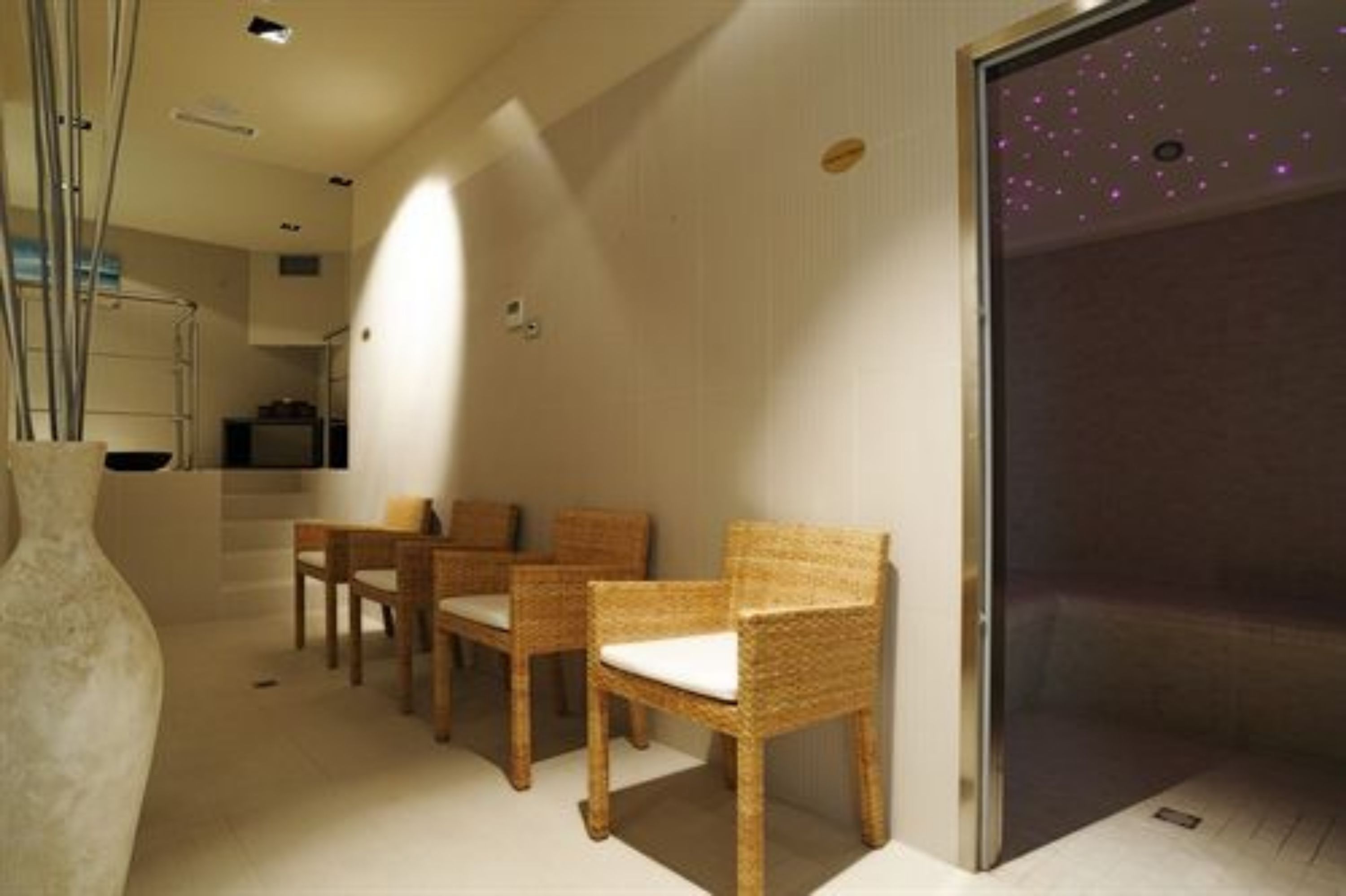 Habitación con zona de estar, sillas de mimbre y un jarrón grande.