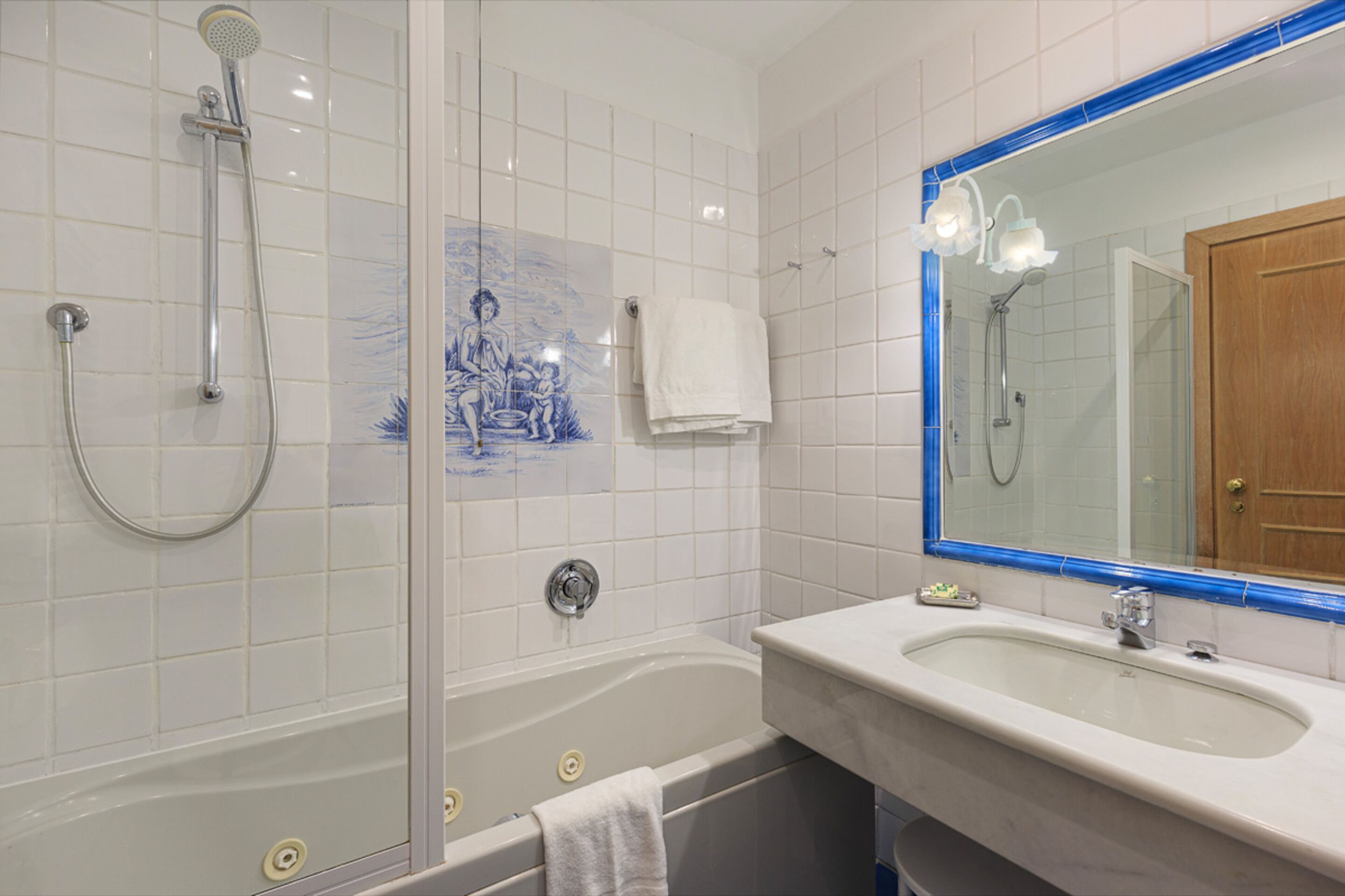 Ein Badezimmer mit einer Badewanne, einer Dusche, einem Waschbecken und einem Spiegel.