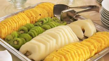 Une assiette de fruits coupés en tranches, notamment du kiwi, de l’ananas et de la mangue, disposés sur un plateau de service en métal.