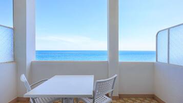 A balcony with a checkered floor, a white table, and two white chairs.