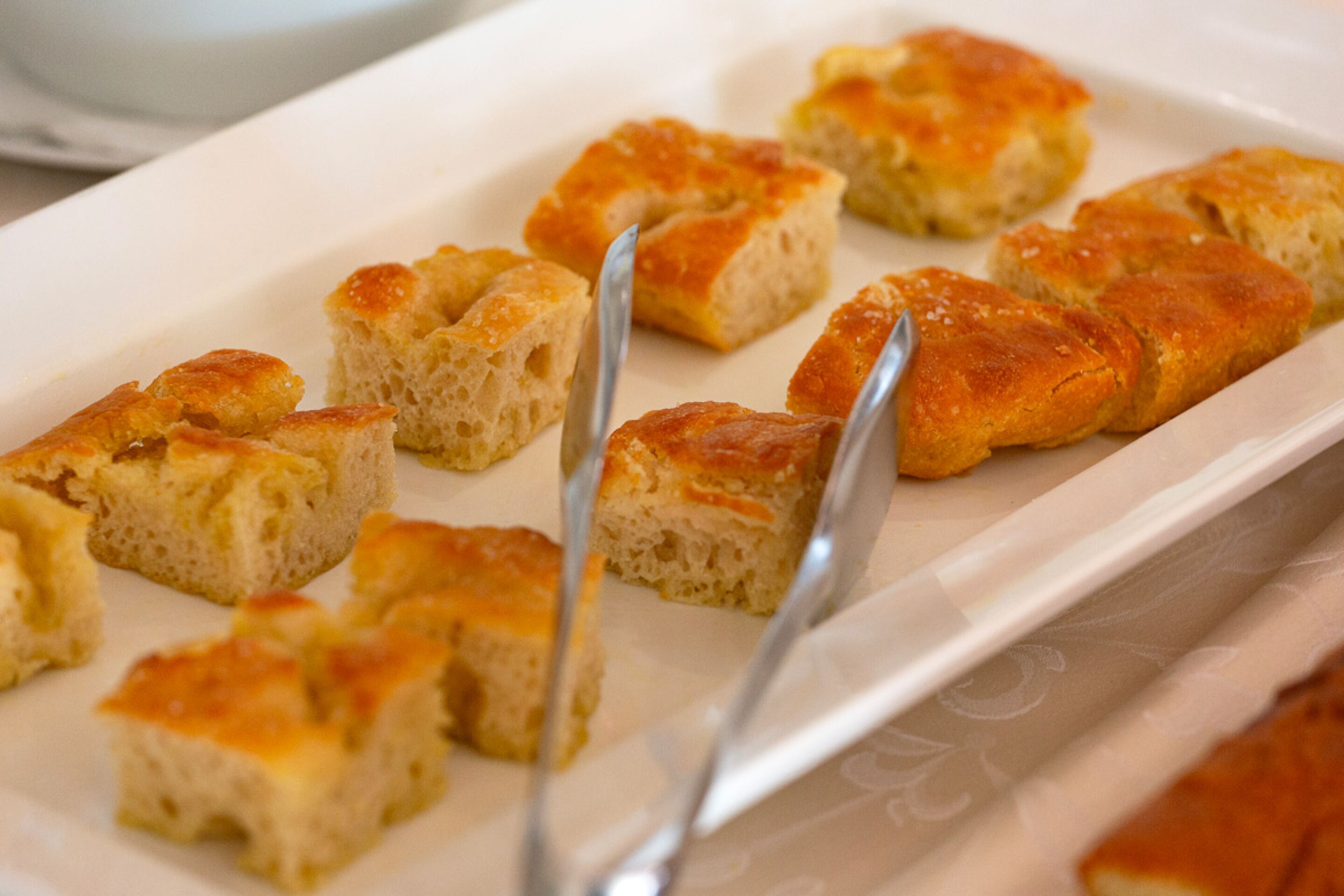A white rectangular plate with several pieces of bread arranged on it.