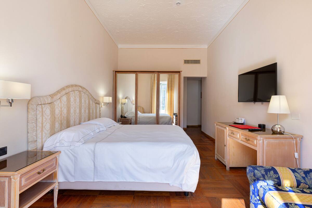 Ein Hotelzimmer mit einem großen Bett, einem Schreibtisch, einem Fernseher und einem Sessel.