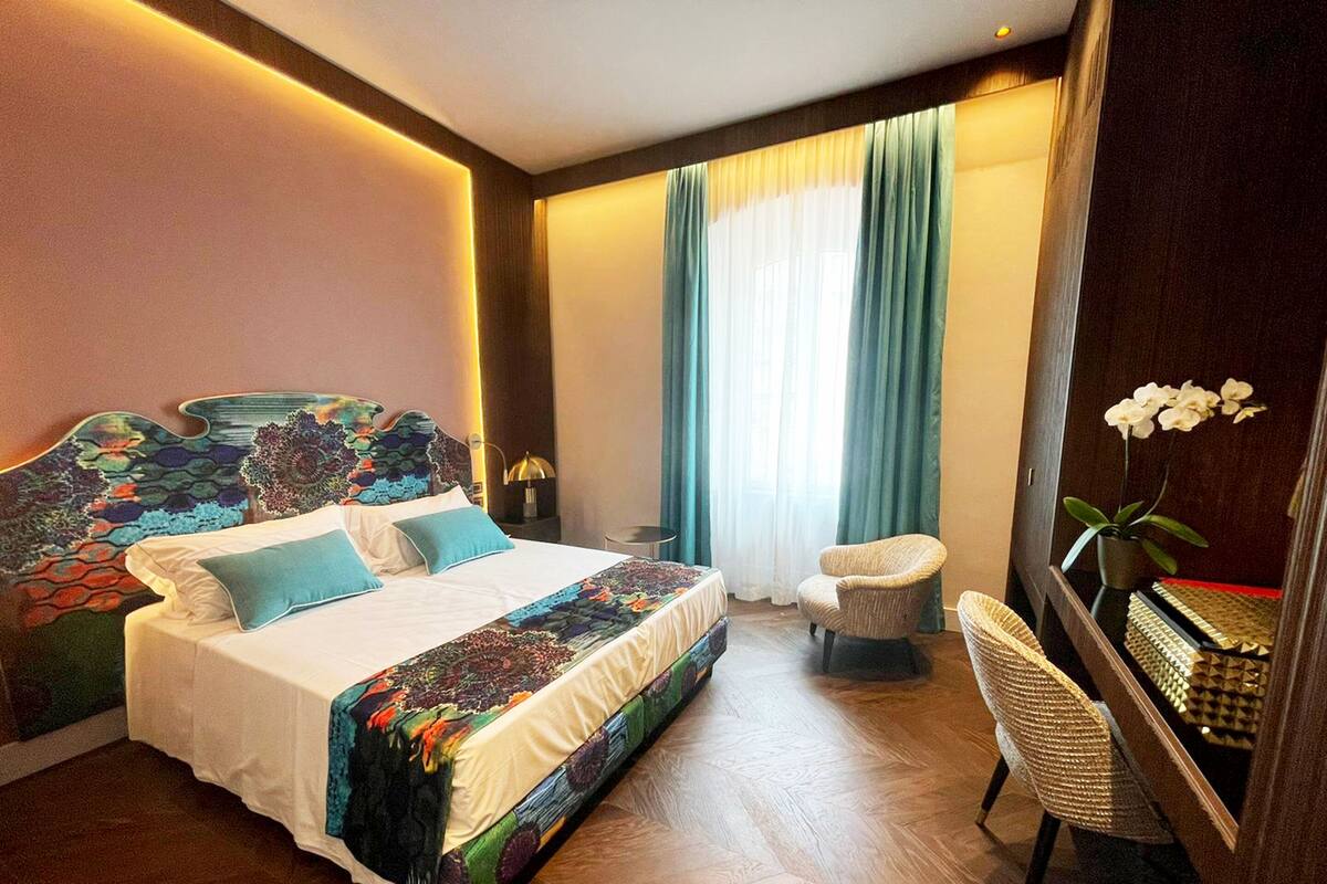 Ein Hotelzimmer mit einem großen Bett, einem Sessel, einem Schreibtisch und einem Spiegel.