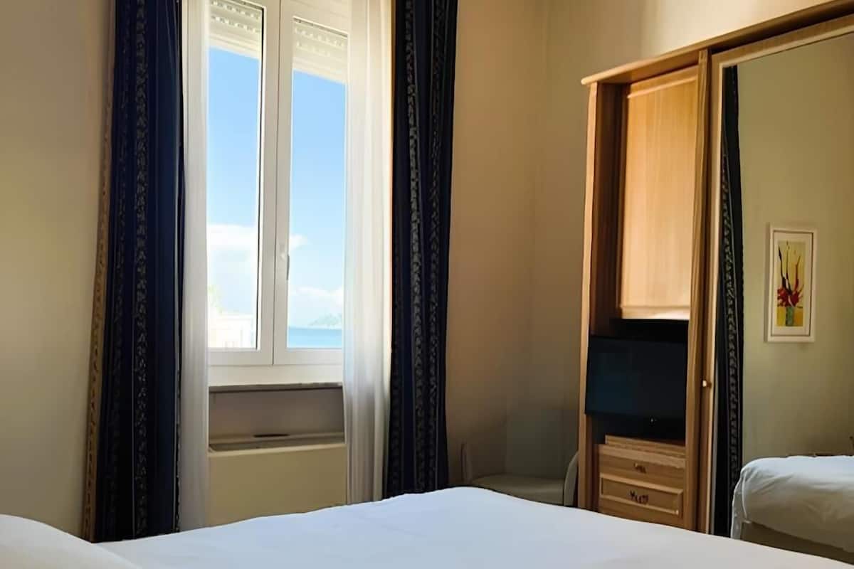 Ein Hotelzimmer mit Bett, Schrank und einem Fenster mit Vorhängen.