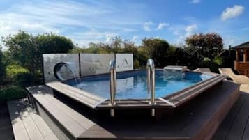 Relax in a hot tub surrounded by lush greenery and a serene natural setting.