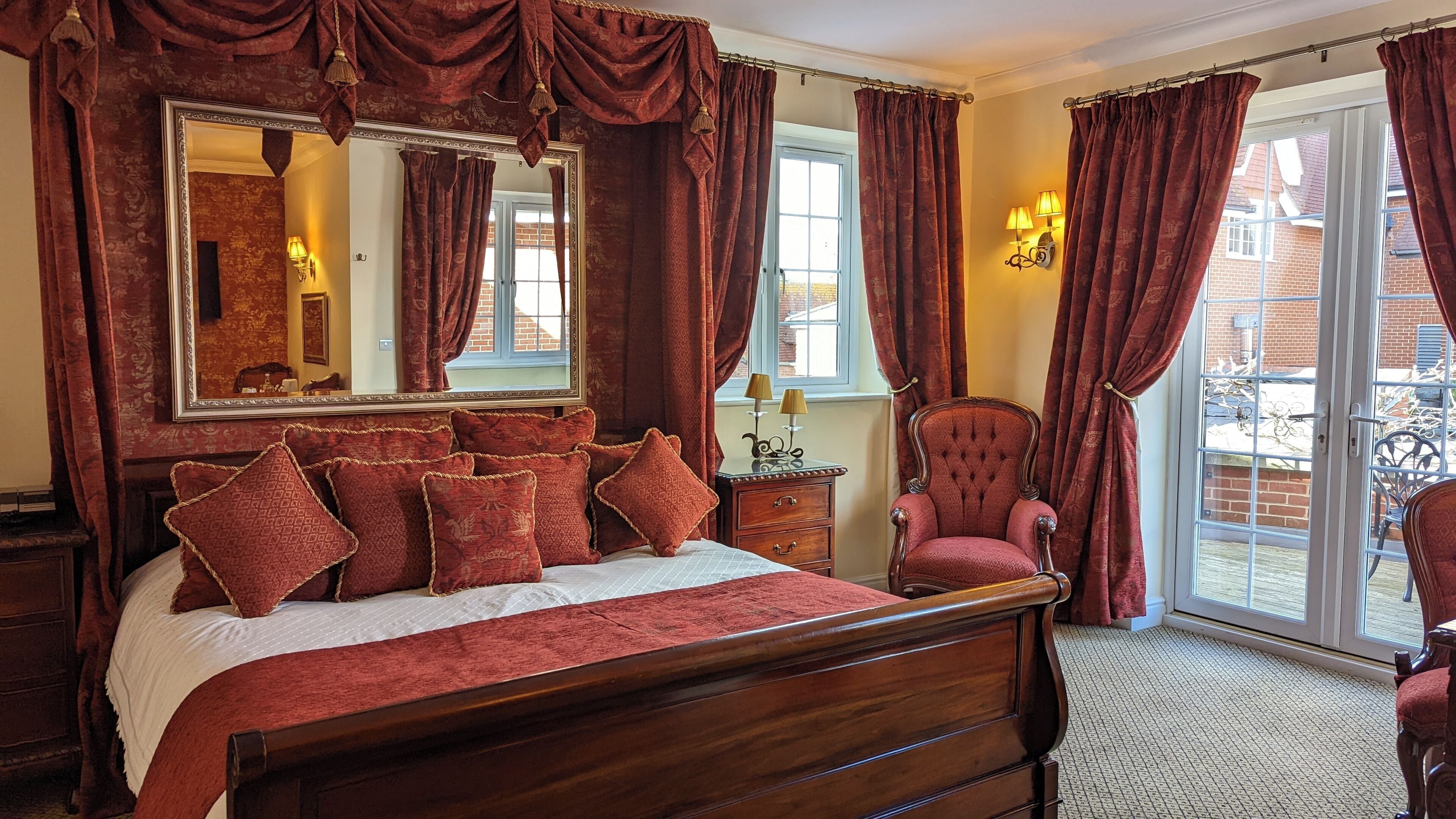 A bedroom with a large bed, a chair, a dresser, and a window with curtains.