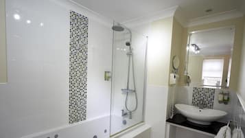 Un baño moderno con ducha envuelta en vidrio, lavabo blanco y salpicadero de azulejos.