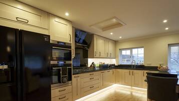 A modern kitchen with a black refrigerator, built-in oven, microwave, and a large window with blinds.