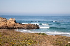 A coastal landscape with rocky formations, a beach, and a clear sky. - The Beach House Inn (Fort Bragg)