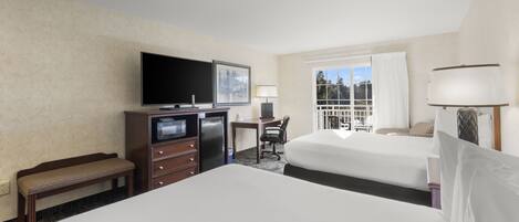 Quarto de hotel com duas camas, uma mesa, televisão e janela com cortinas.