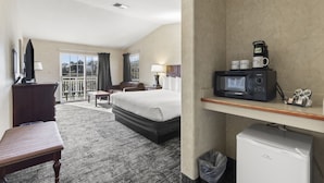 A hotel room with a bed, a desk, a chair, a small table, a microwave, a coffee maker, and a mini-fridge. - The Beach House Inn (Fort Bragg)
