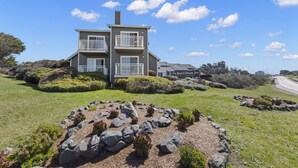 A two-story building with a balcony, surrounded by landscaped gardens and a clear sky. - The Beach House Inn (Fort Bragg)