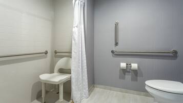 A bathroom with white walls, a white toilet, a white chair, and a shower curtain.