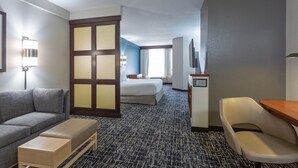 Hotellihuone, jossa on sohva, sänky, työpöytä ja tuoli.