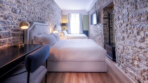 A bedroom with stone walls, a bed, bedside tables, a lamp, and a view of the room. - Hotel Acadia (Québec City)