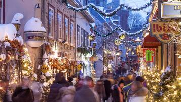 A snow-covered street with festive decorations and people walking.