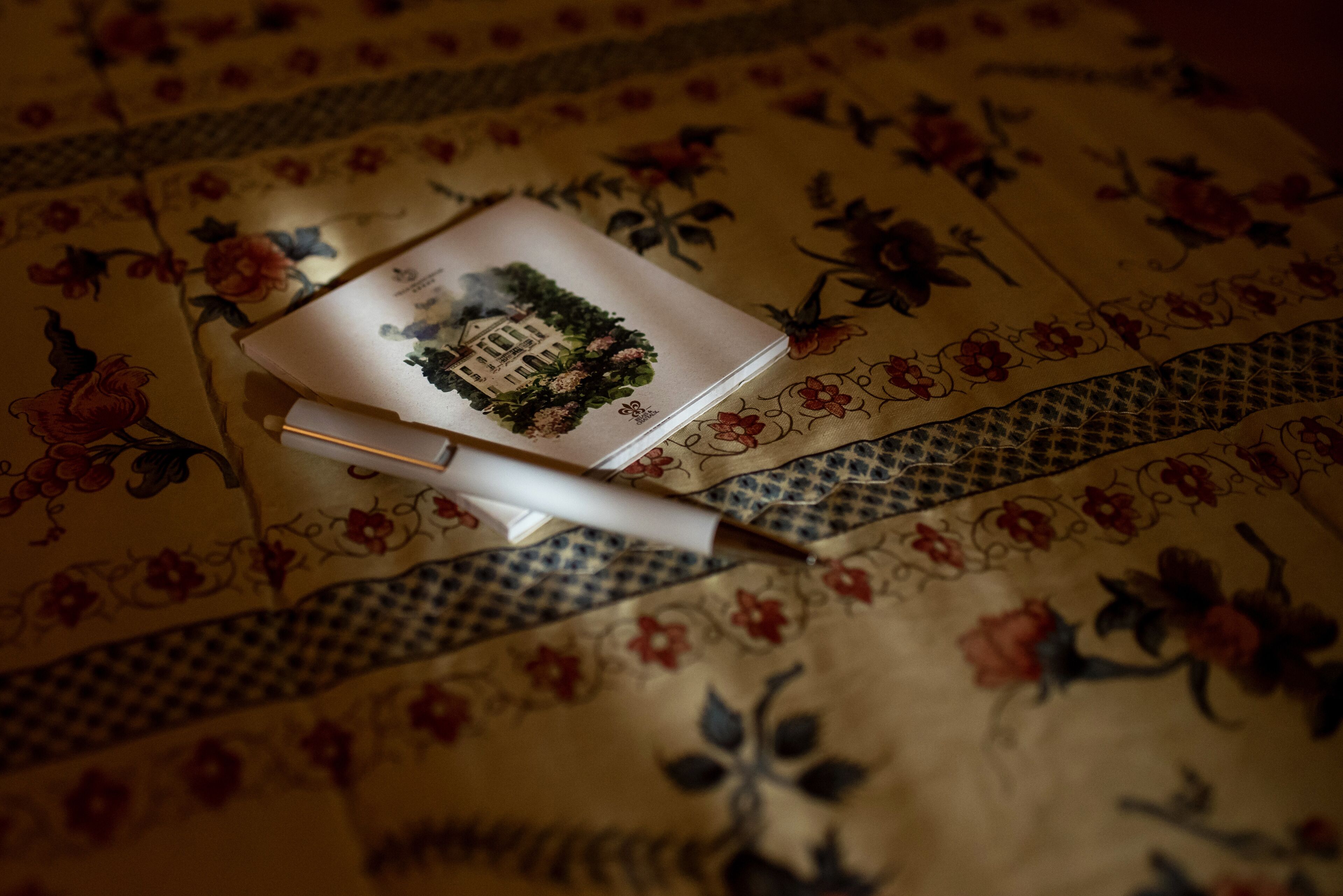 Un libro con un diseño floral sobre un mantel estampado.
