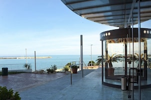 Una estructura con paredes de vidrio y techo curvo que da vistas a la costa.