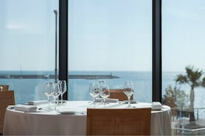 A dining table set for four with a view of the sea and a pier in the background. - Hotel Flamingo (L'Ampolla)