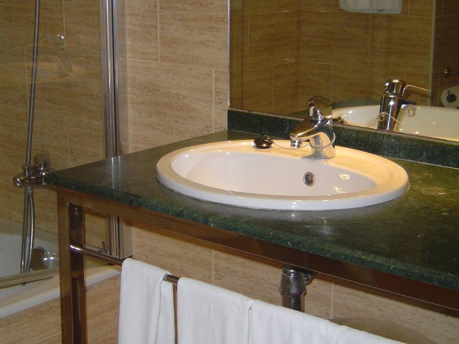 A bathroom with a sink, mirror, and shower.
