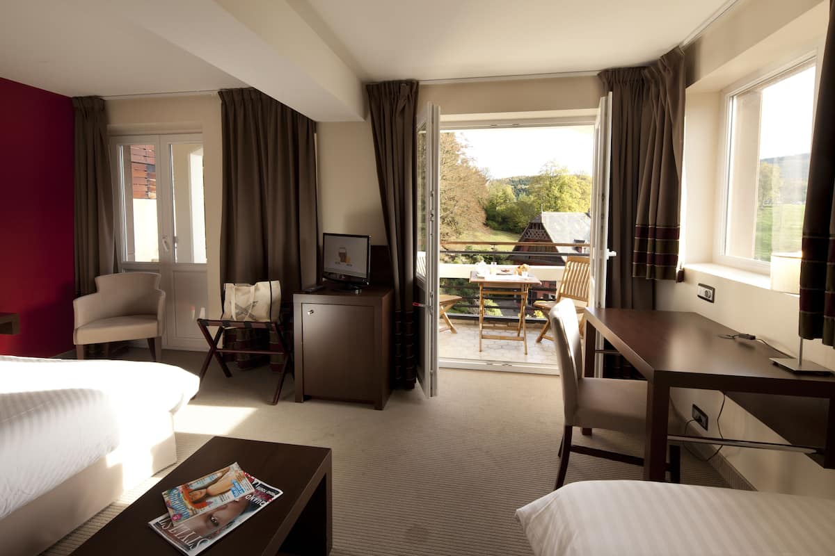 Een hotelkamer met een bed, een bureau, een stoel en uitzicht op het omliggende landschap.
