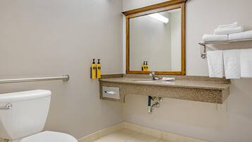 A bathroom with a toilet, sink, mirror, and towel rack.