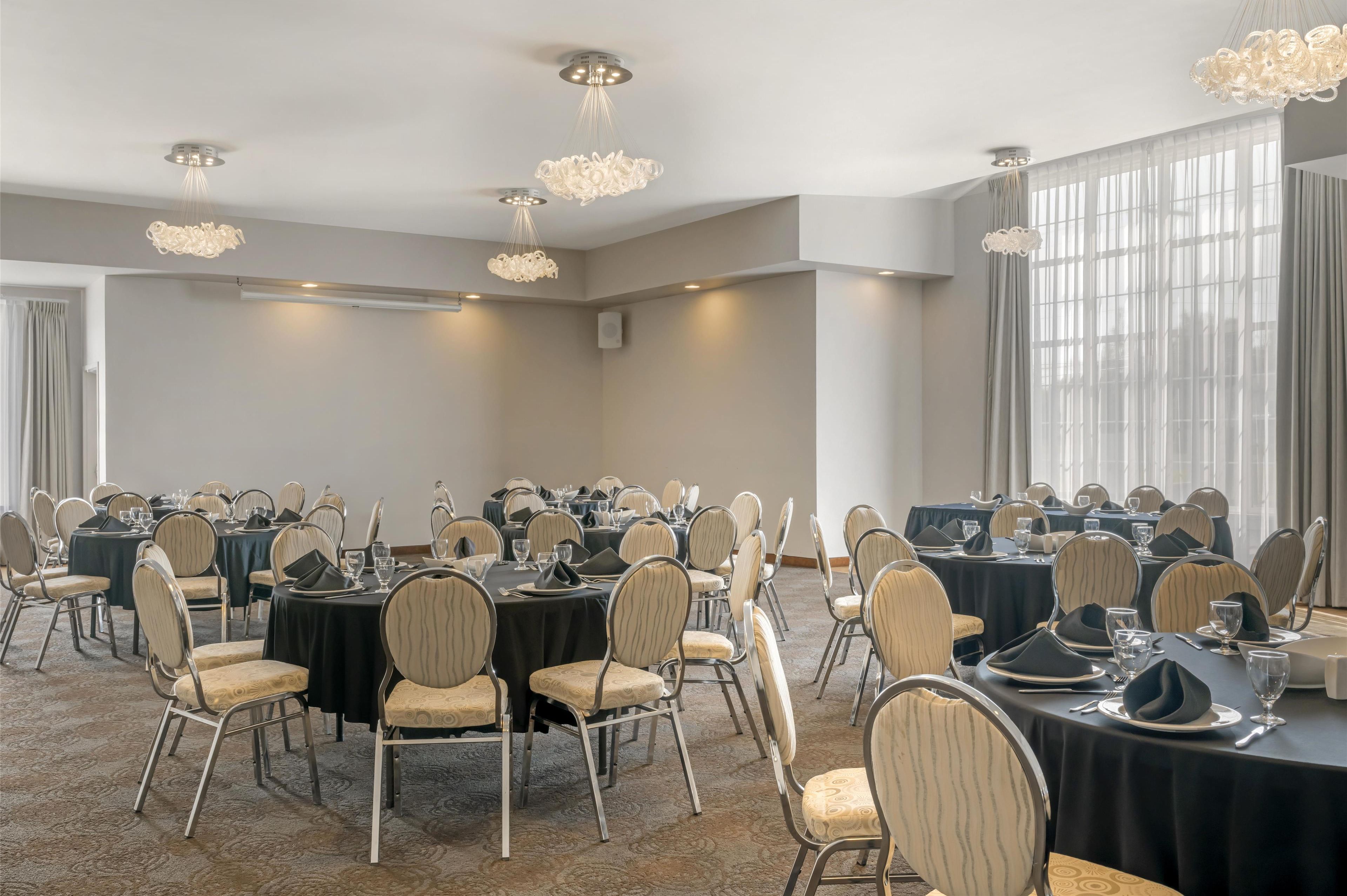 Une salle de conférence équipée de tables rondes, de chaises et de lustres.